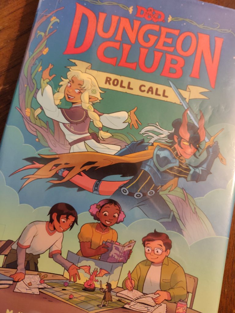 picture of the D&D Adventure Club book with the cover reading "D&D Adventure Club Roll Call" and pictures showing Sir Corius, another party member, and the D&D club playing a game over a table