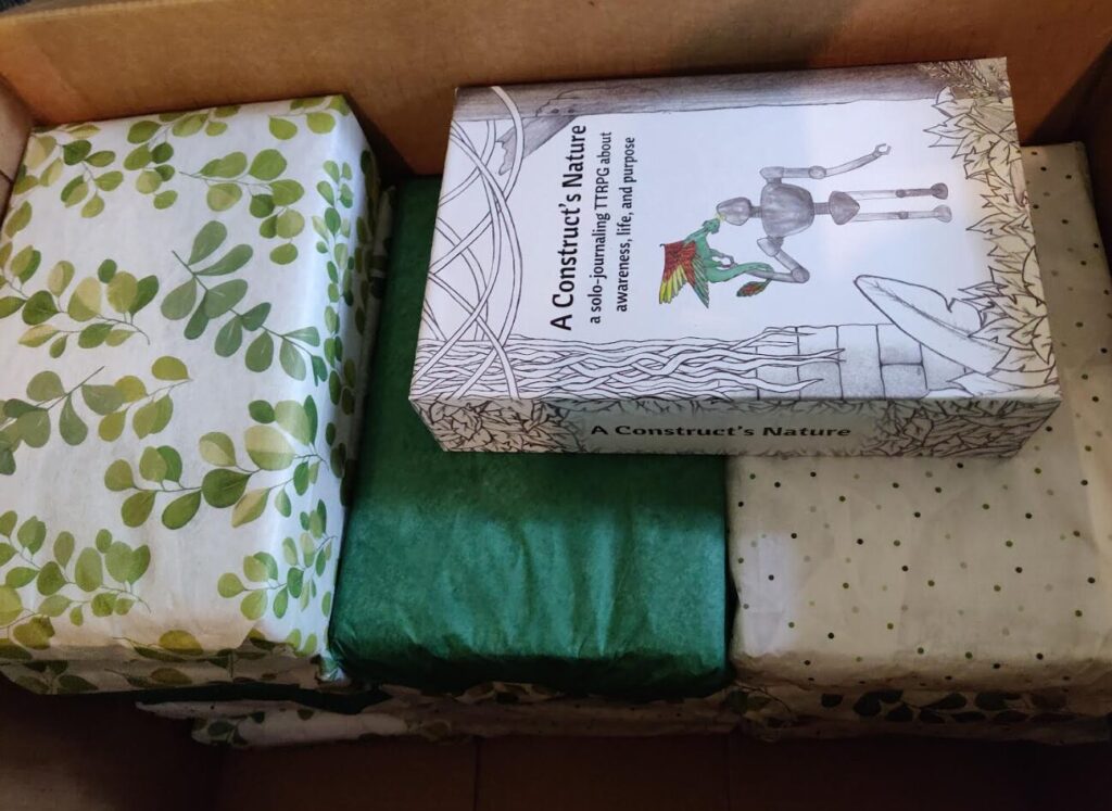 several packages wrapped in green, leaf pattern, and polka dot paper. A copy of the ACN box rests on top.
