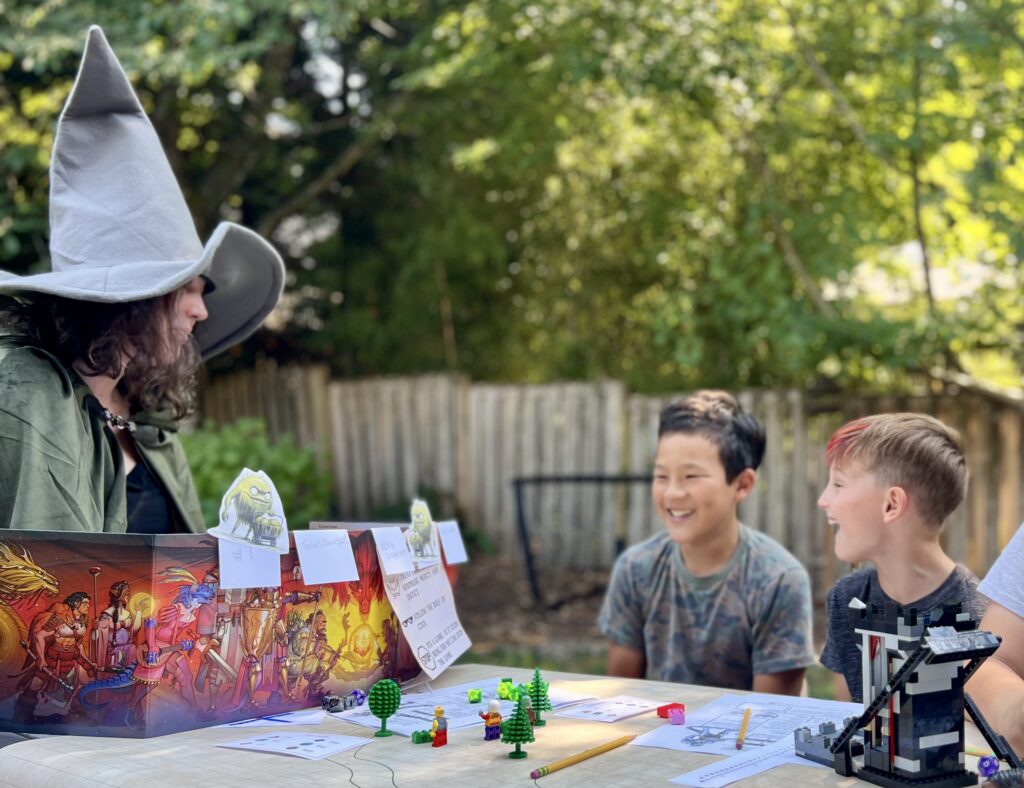a photo of a group of kids and a GM sitting around a table ready to play a game