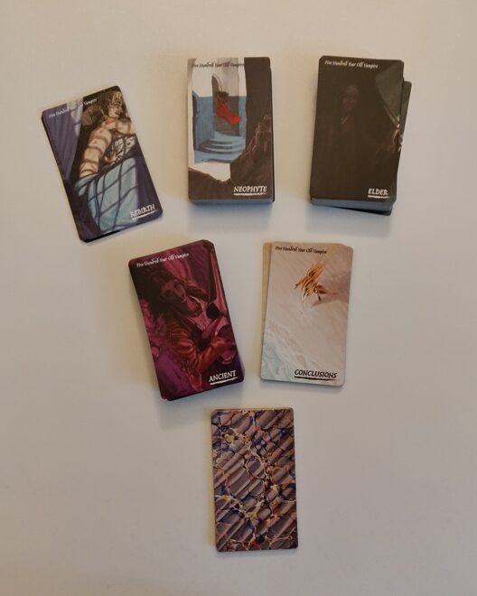 a photo fo the the 6 decks of cards for 500 Year Old Vampire set out
