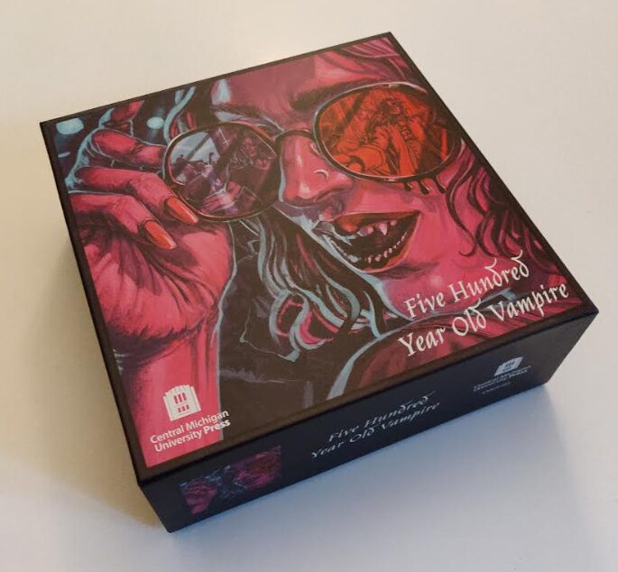 a photo of the box for 500 Year Old Vampire showing a picture of a vampire wearing sunglasses and bearing their teeth slightly