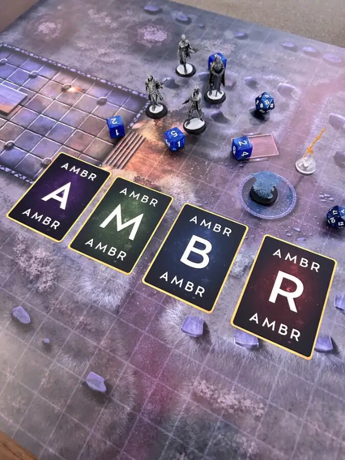 a photo of the AMBR cards, all flipped over and laid out across a gaming table with minis and dice and a map