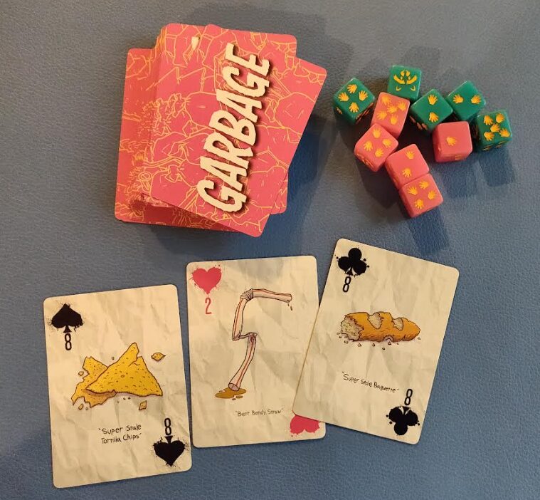 a photo of the Garbage deck from Garbage & Glory alongside a set of racooon themed dice