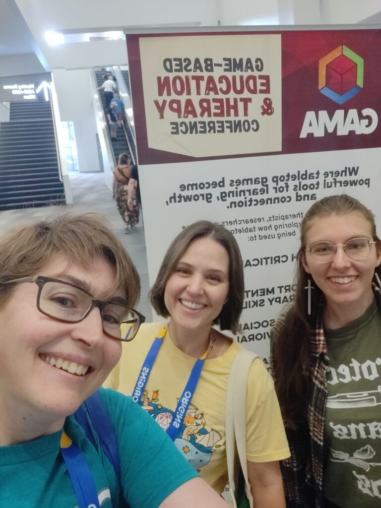 a photo showing (from left to right) Steph Campbell, Katie Lear, and Jaclyn Lewis standing in front of the GBET conference sign
