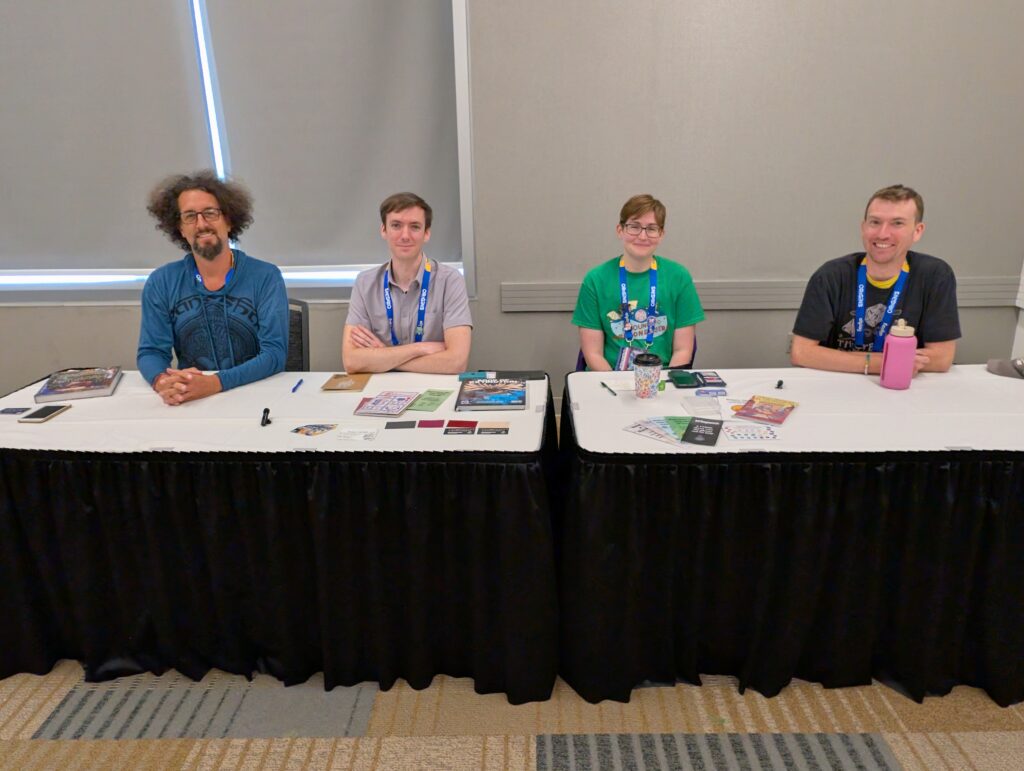 a photo of (from left to right) Zach Reznicheck, Lucas Zellers, Steph Campbell, and Andy Charlton sitting at a table, ready for their panel on dayjobs and TTRPGs