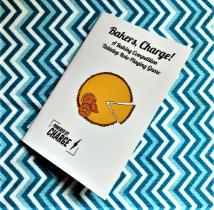 a photo of the cover of Bakers, Charge! featuring art of an orange pie with the slice being cut and removed from it