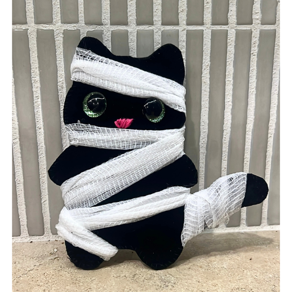 shows a photo of the monthy craft, which is a felt cat wrapped in guaze to look like a mummy